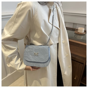Detail of light blue saddle bag with cloud texture, butterfly clasp and chain strap