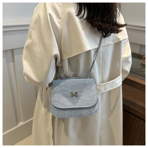 Detail of light blue pleated shoulder bag featuring a silver butterfly clasp and chain