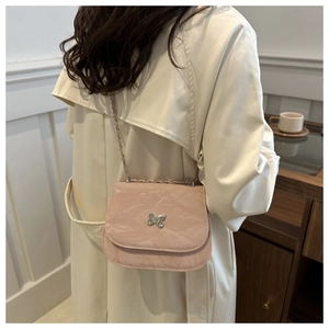 Detail of pink pleated crossbody bag with silver butterfly buckle on white coat