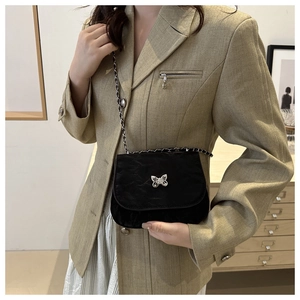 Detail of black saddle bag featuring silver butterfly clasp and leather chain strap
