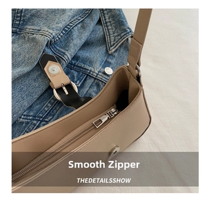 Detail shot of smooth silver zipper and magnetic buckle on beige faux leather crescent bag