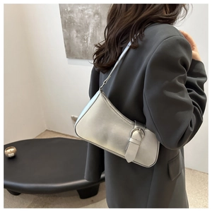 Detail of silver metallic crescent bag with large buckle and sleek shoulder strap