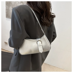 Detail view of silver crescent bag with metallic finish and buckle strap on model