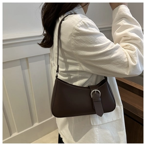 Detail view of dark brown crescent underarm bag with silver buckle on a model