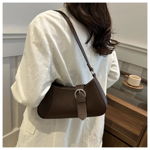 Detail view of dark brown crescent underarm bag with silver metal buckle on leather strap