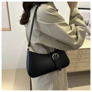 Close-up of black leather underarm bag with silver round metal buckle and slim shoulder strap