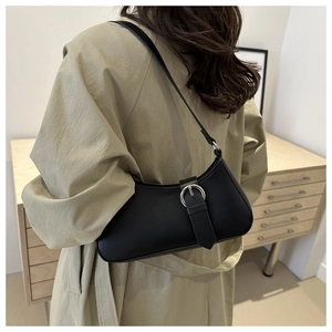Detail of minimalist black leather underarm bag with oversized silver ring buckle hardware