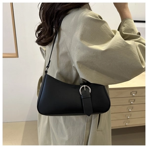 Vista laterale della borsa baguette in pelle nera con fibbia argento e tracolla sottile