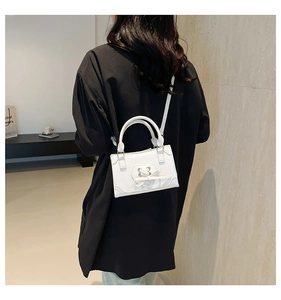 Détail d'un sac à main blanc avec nœud en forme de cœur porté par un mannequin