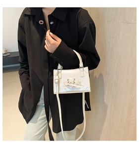 Dettaglio borsa bianca in pelle con motivo a cuore traforato e fiocco decorativo