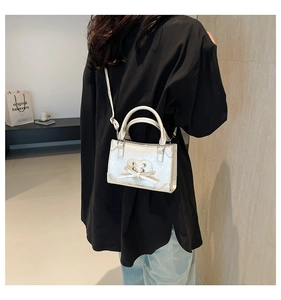 Modèle portant un mini sac bandoulière blanc perle avec cœur et nœud élégant