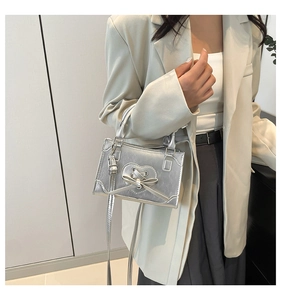 Detail of silver metallic crossbody bag with heart cutout and ribbon on model
