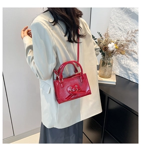 Detail of red glossy leather bag featuring a heart-shaped cutout with ribbon tie detail