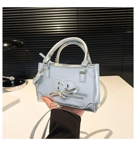 Dettaglio mini borsa argento con cuore 3D, lacci a nastro e doppi manici tondi