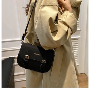 Detailed view of vintage black saddle bag with gold metal buckles and fashion inscription