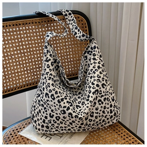 Detail of leopard print canvas bag displayed on a rattan chair with soft lighting