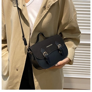 Detail of a chic black leather saddle bag with double buckle straps and elegant top handle