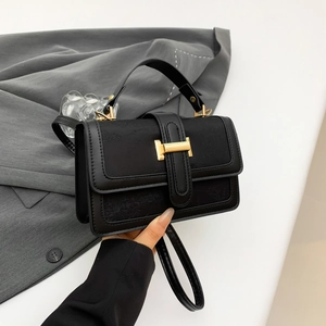 Elegant black leather crossbody bag with golden H-buckle and subtle embossed patterns