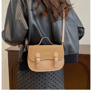 Khaki crossbody bag with top handle worn by model in black leather jacket outfit