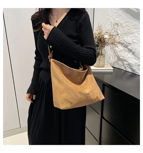 Detail of camel suede tote bag featuring a decorative knotted shoulder strap and soft texture