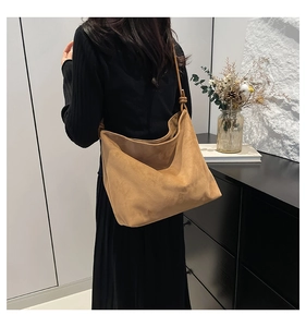 Minimalist camel tote bag with knot detail shown on model in a modern office setting