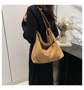 Close-up of the stylish knotted strap detail on a large brown matte suede tote bag