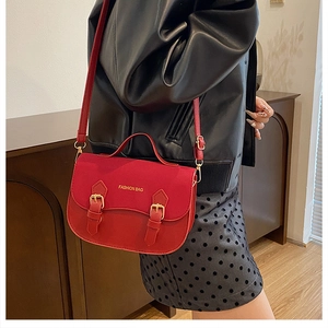 Detail of red crossbody handbag with Fashion Bag logo shown with casual model outfit