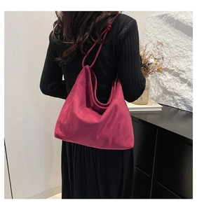 Detail of burgundy suede tote bag featuring a decorative knot on the shoulder strap