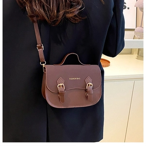 Retro dark brown crossbody bag with dual buckle straps and gold-toned fashion text