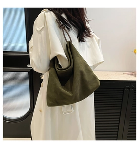 Macro view of a moss green suede hobo bag with a dark brown leather ring handle detail