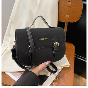 Detail of black leather handbag with gold Fashion Bag lettering and metal buckles