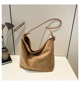 Detail of caramel suede hobo bag featuring decorative knots on soft shoulder straps