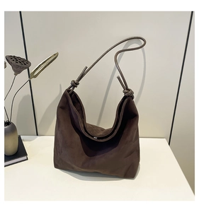 Detail of dark brown suede tote bag with stylish knot strap and soft matte texture