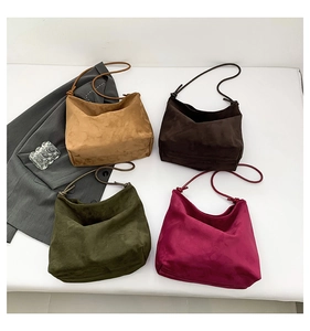 Flat lay of large matte hobo bags in brown, green, and pink on white background