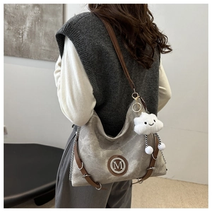 Detail of grey canvas tote bag with M logo, chain strap and cloud plush charm detail
