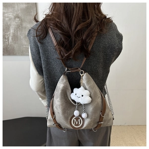Détail du sac à dos en toile grise avec lanières en cuir et breloque nuage en peluche