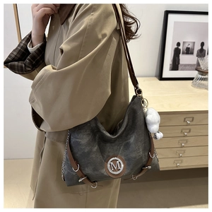 Detail of grey canvas tote with brown leather trim and M-logo metal buckle decoration