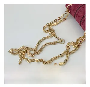 Close-up of golden metal chain strap on a burgundy suede mini crossbody bag detail