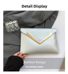 Macro shot of silver envelope clutch with V-shaped gold metal trim and quilted stitching