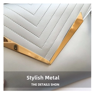 Detail of V-shaped quilted leather texture and premium gold metal clasp on square handbag