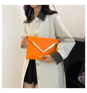 Detail of orange envelope clutch with gold V-shaped metal bar and stitching pattern