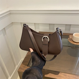 Borsa baguette marrone in ecopelle con grande fibbia argentata in un ambiente lifestyle