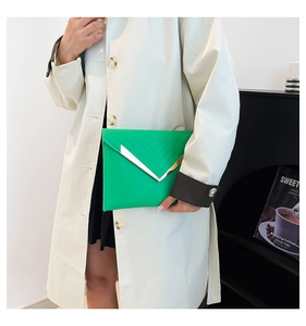 Detail of bright green envelope clutch with V-shaped metal trim and leather texture