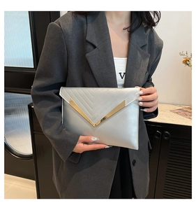 Close-up of silver envelope clutch featuring V-shaped quilting and gold metal hardware