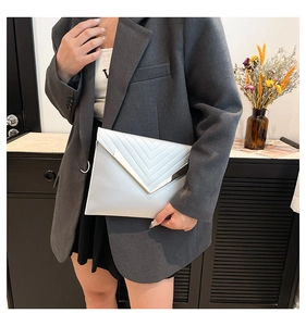 Detail of silver envelope clutch bag with chevron stitching and V-shaped metal trim