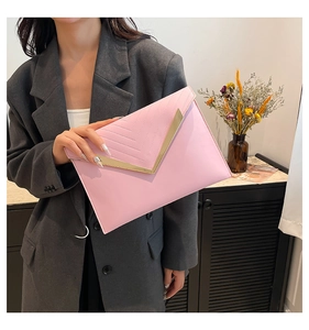 Detail of pink quilted envelope clutch with gold V-decoration held by model