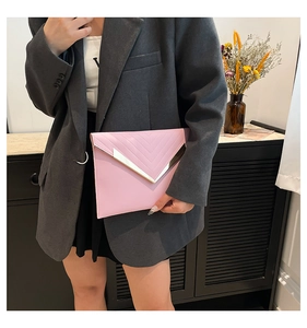 Detail of pink quilted envelope clutch with gold V-shaped metal trim and chevron stitching