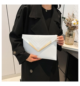 Detail of white envelope clutch with V-quilted stitching and gold metal hardware
