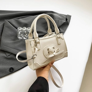 Piccola borsa a tracolla beige in ecopelle con motivo a cuore e fiocco moda