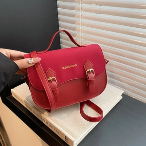 Two-tone red saddle bag with top handle and crossbody strap against a stylish background